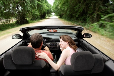 image of couple driving in a convertible