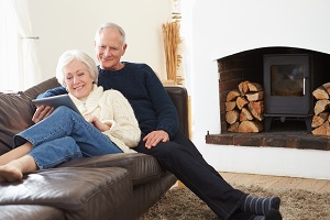 senior couple sitting on couch looking at tablet