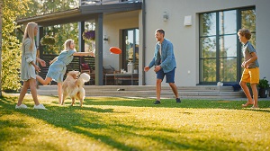 family play frisbee with dog in backyard